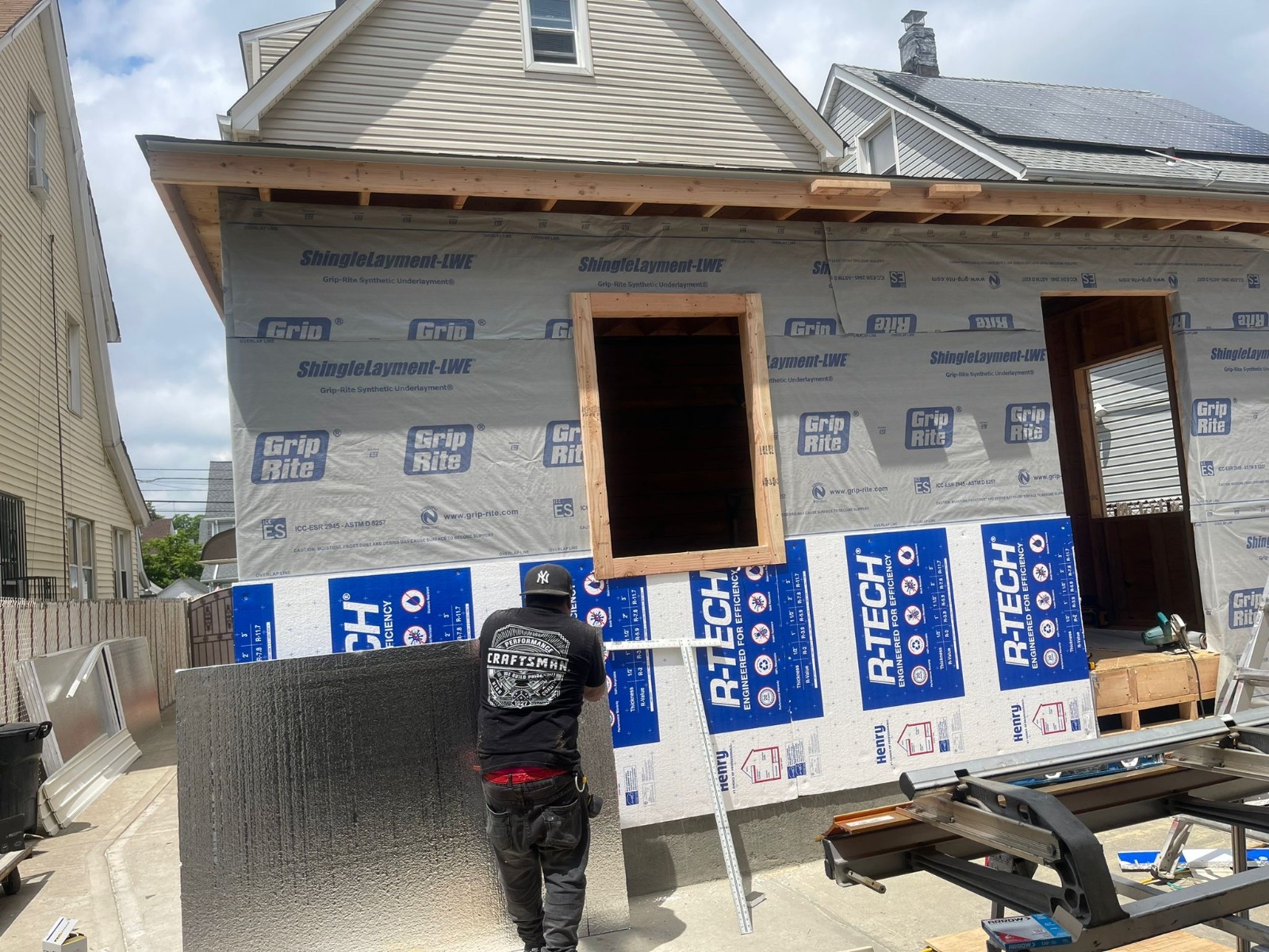 A residential home mid-construction, wrapped and framed, on an MPM job site