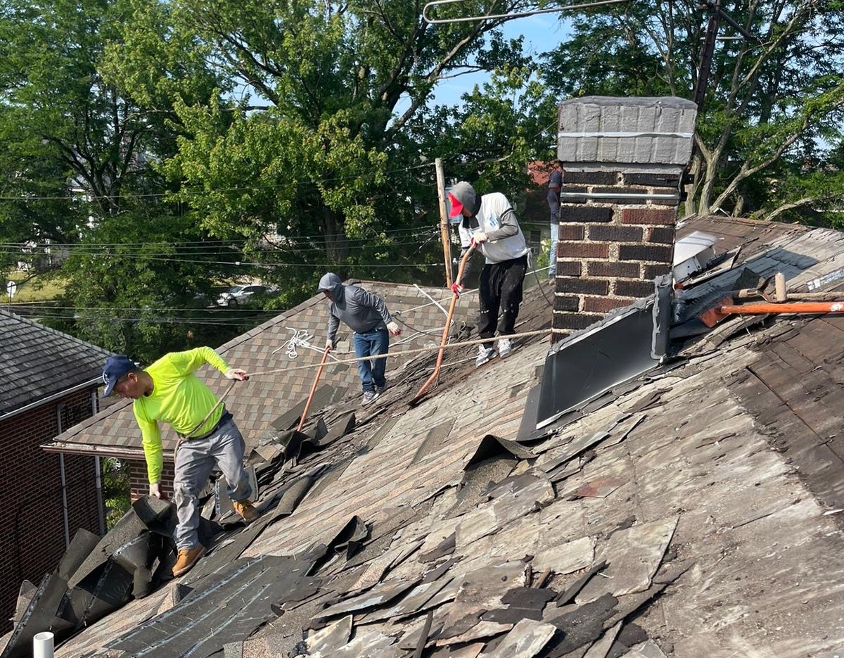 An MPM crew working on a sloped roof, mid tear-off and re-roof