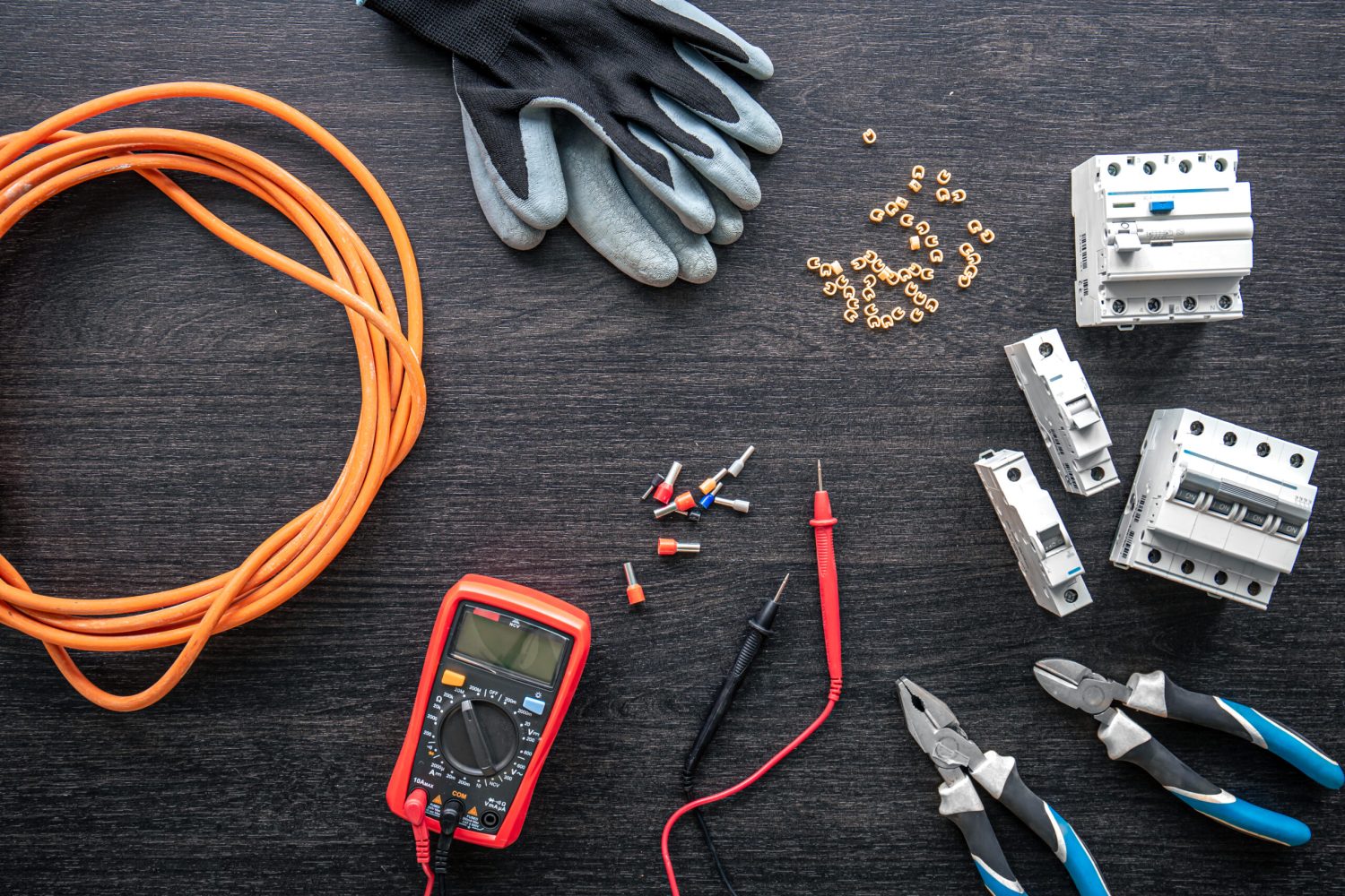 A flat lay of electrical tools on a wooden workbench