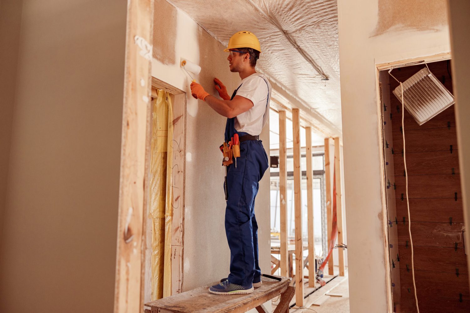 A wall being painted with a roller inside a home under construction